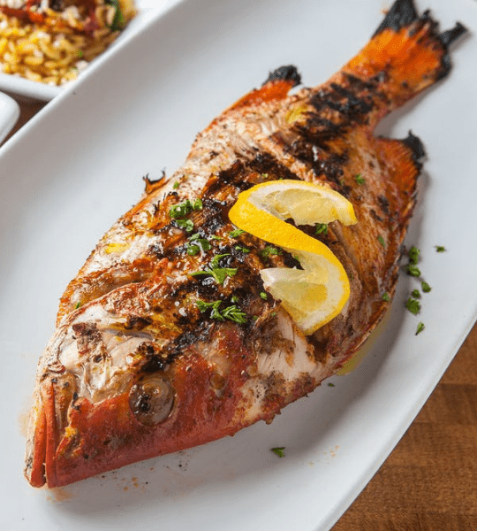 Acropolis Greek Taverna - Grilled Red Snapper: Whole Red Snapper Marinated in Rosemary, Garlic, Extra Virgin Olive Oil and Fresh Lemons Charbroiled to Perfection and Topped with Our House Lemon Herb Marinade. With Choice of One Side.