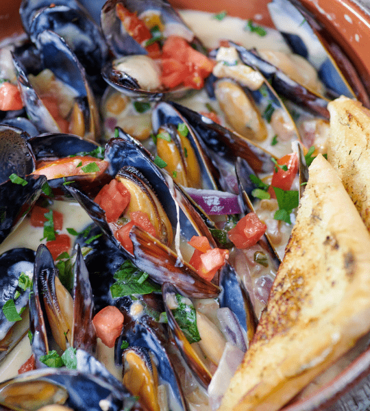 Acropolis Greek Taverna - Ouzo Mussels: Sautéed Mussels With Garlic, Onions, Basil, Fresh Tomato, Ouzo And Santorini Wine. Served With Garlic Bread.
