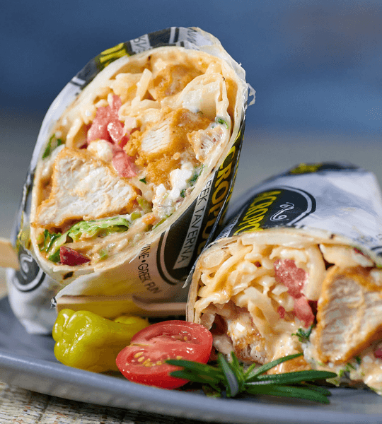 Acropolis Greek Taverna - Buffalo Chicken Wrap: Golden Fried Chicken Breast Tossed in Buffalo Sauce, And Wrapped in a Tortilla with Mozzarella Cheese, Mixed Vegetable Slaw, and Blue Cheese Dressing.