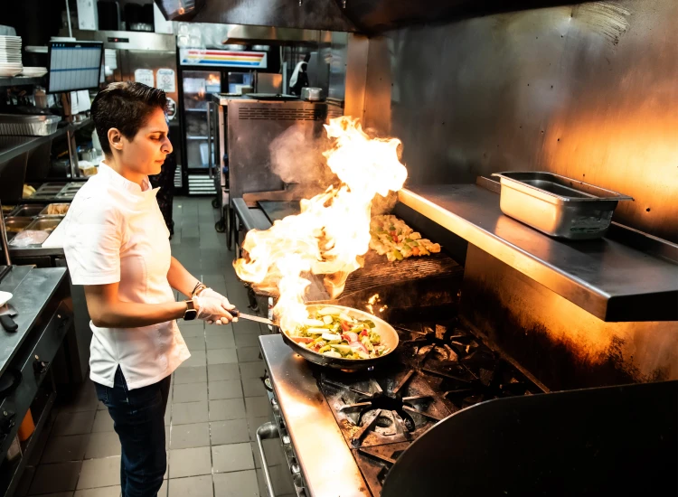 Acropolis Greek Taverna chef preparing flaming Saganaki, a signature dish.