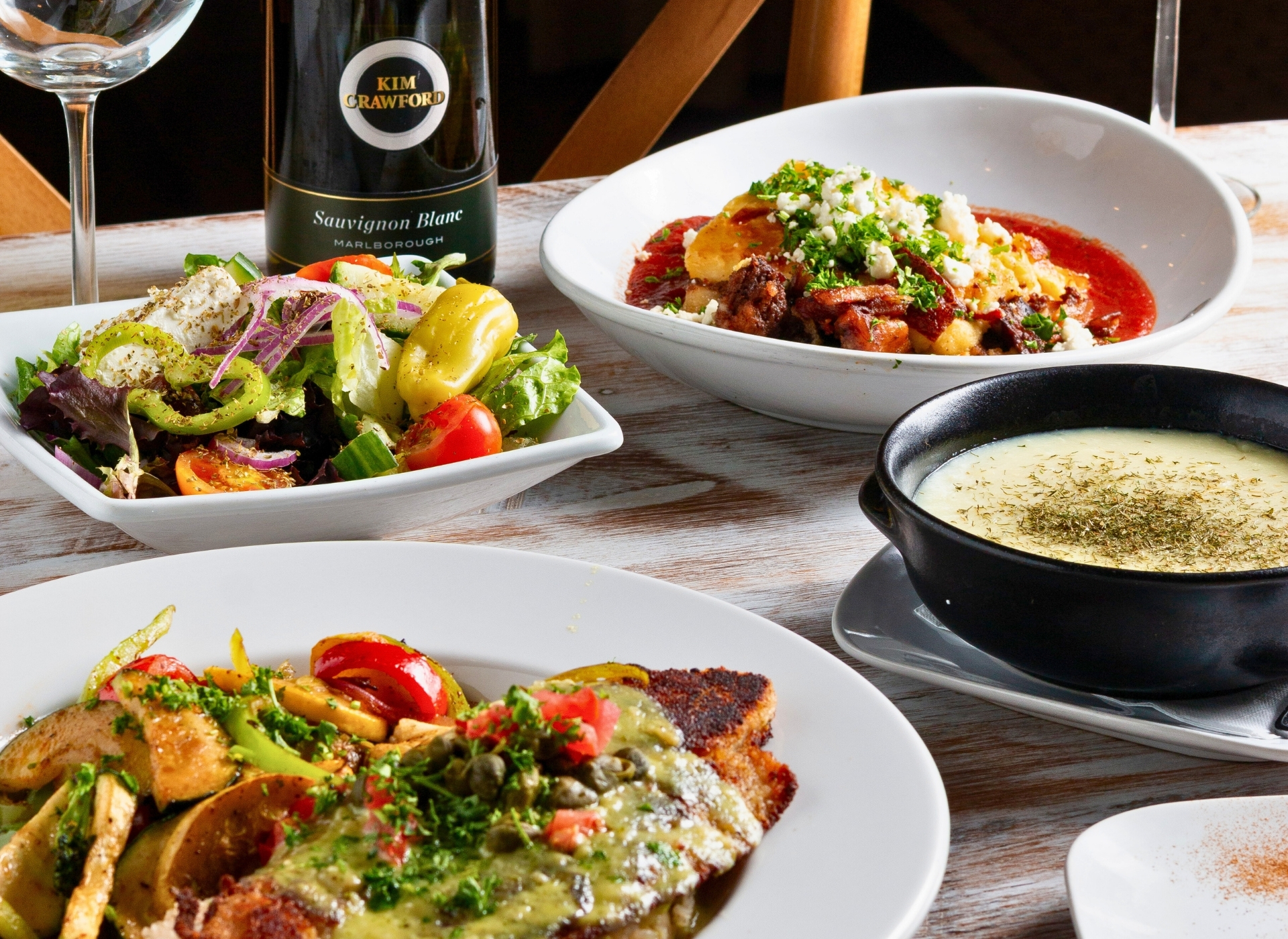 Greek and Mediterranean dishes at Acropolis Greek Taverna: Saganaki, salad, and pasta Santorini.
