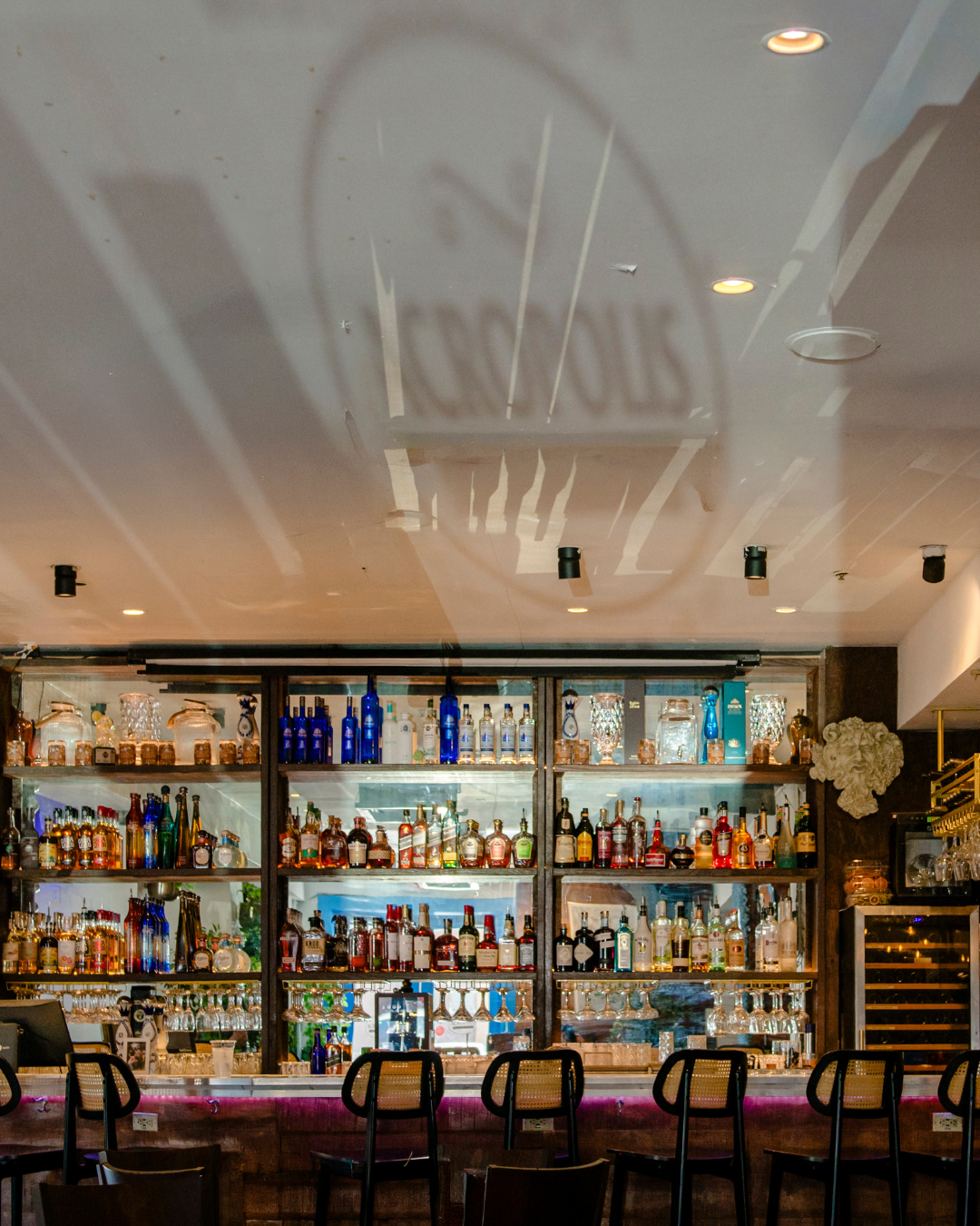 Full liquor bar display and logo ceiling at Acropolis Greek Taverna South Tampa