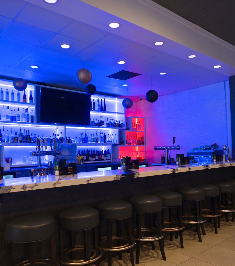 Acropolis Greek Taverna full bar with colorful lighting and stools.