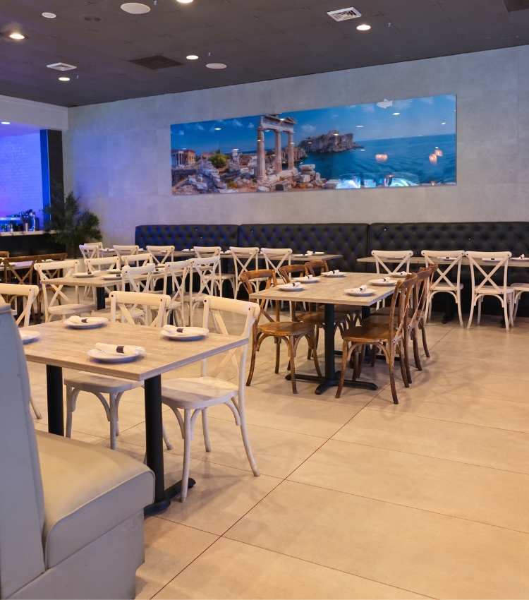 Acropolis Greek Taverna main dining room with tables and booths and Greek coastal artwork.
