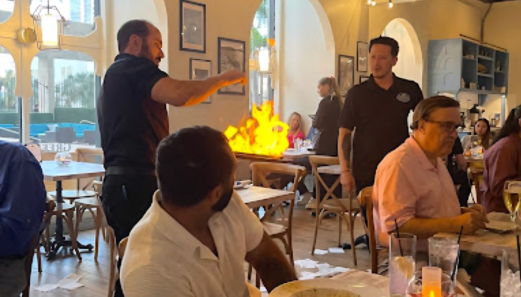 Acropolistaverna Orlando: Greek restaurant ambiance with Saganaki preparation and diners.
