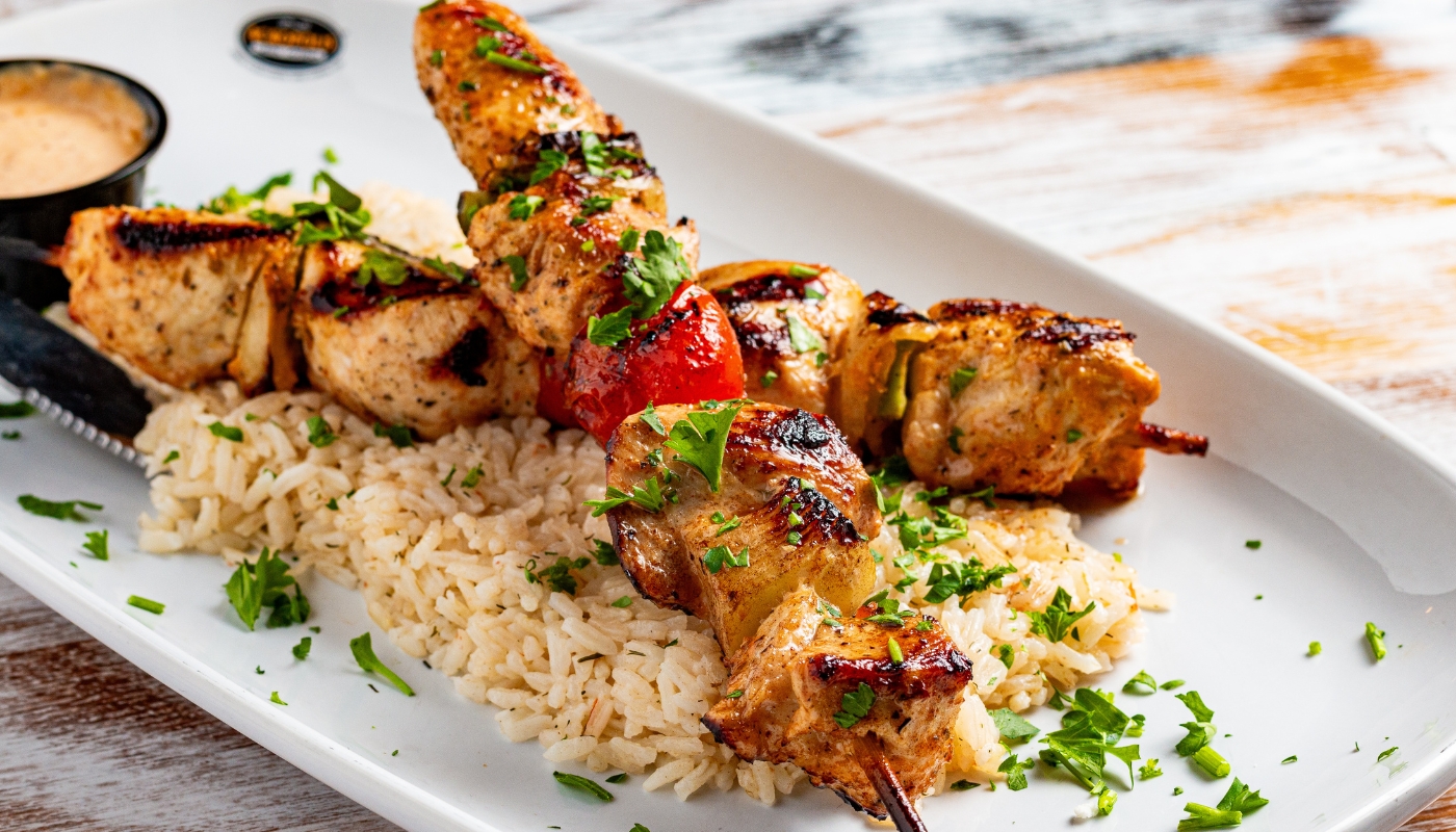 Acropolis Greek Taverna signature dish: grilled chicken kabobs with rice and tomato, authentic Greek cuisine in Orlando.