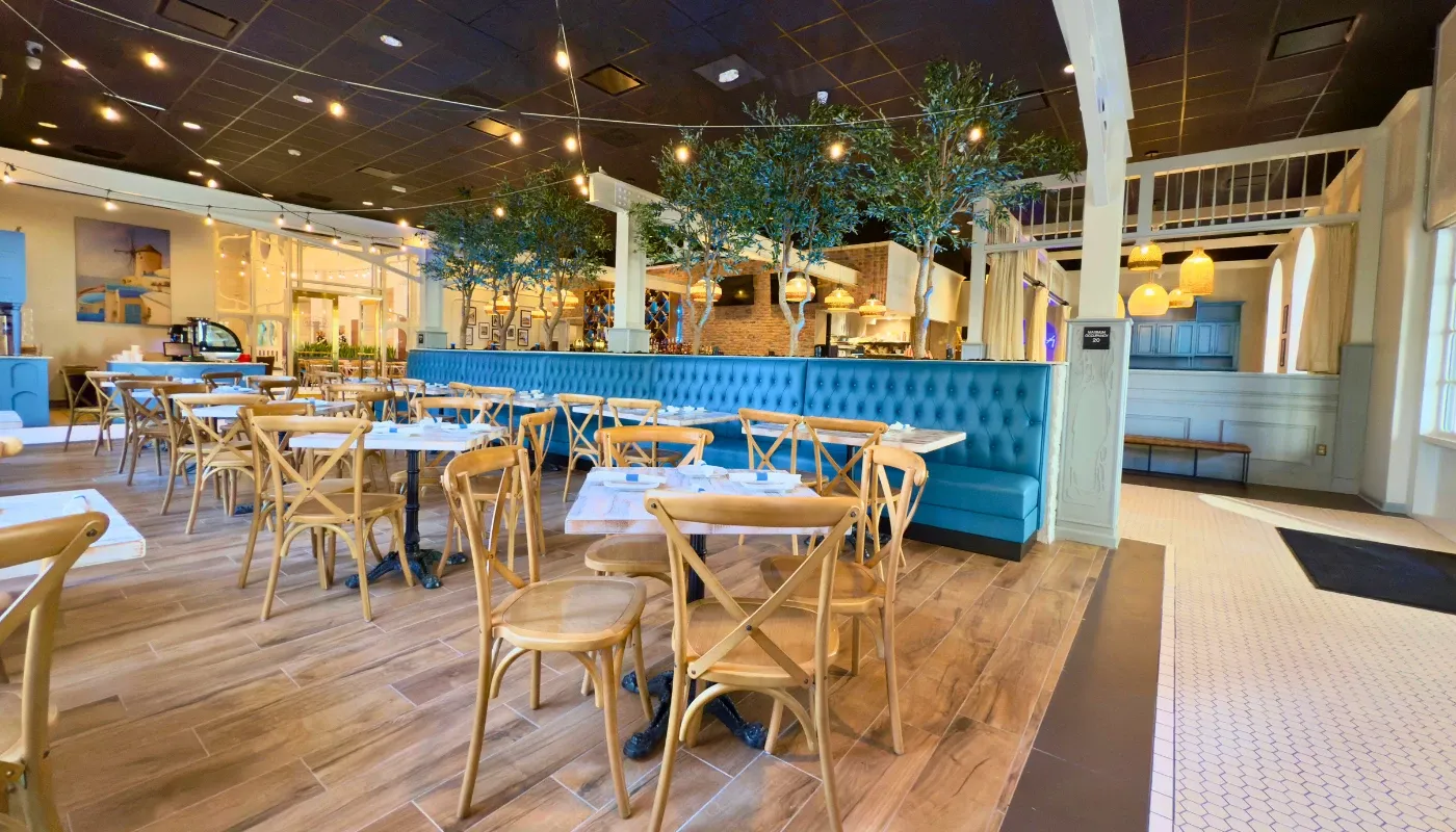 Acropolis Greek Taverna interior with blue seating and wooden tables, showcasing a vibrant Orlando dining experience.