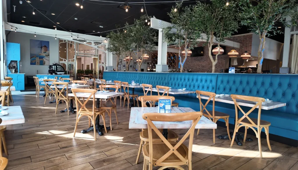 Dining room at Acropolis Greek Taverna Orlando with blue banquette seating, olive trees, and string lights